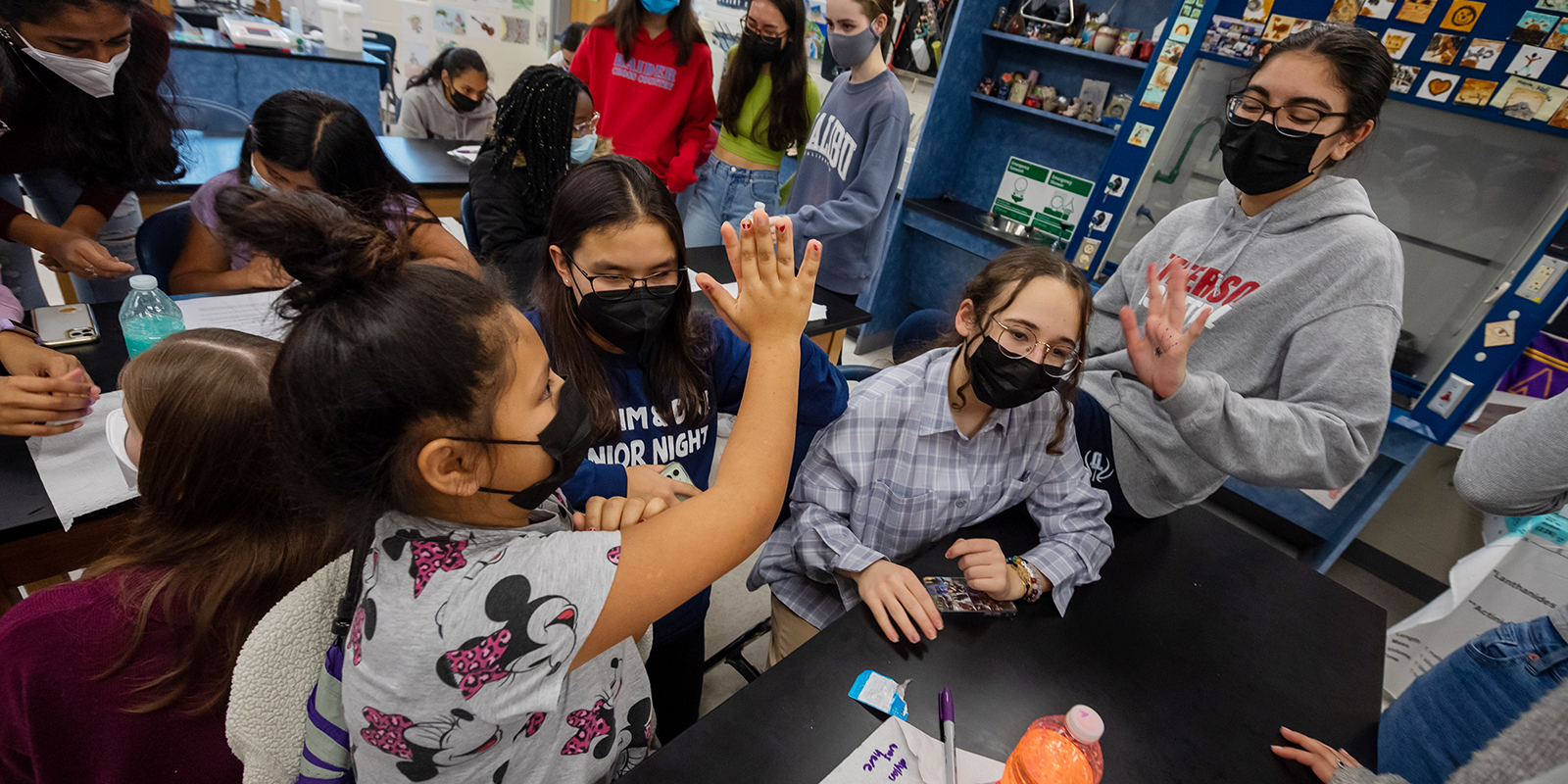 A TJHSST student high-fives a Weyanoke ES student she mentors as part of the Women Interested in Science and Engineering Club.